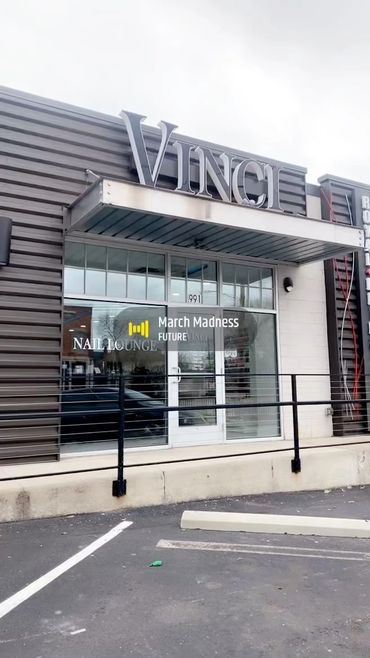 Exterior view of Vinci Nail Lounge with modern signage and parking spaces.