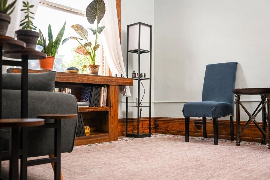 Chair and loveseat facing each other in the counseling office, bookshelf by the window