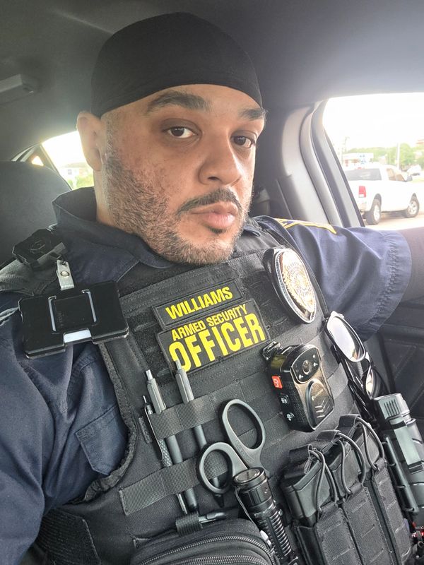 Armed security officer in uniform sitting inside a vehicle.