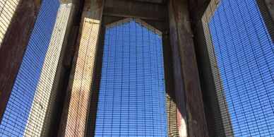 Looking up inside a structure with metal grates and blue sky.