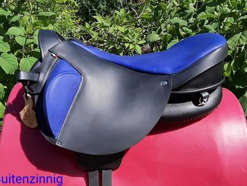 Black and blue horse saddle outdoors.