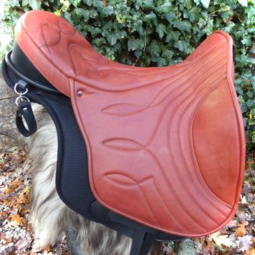 Brown leather horse saddle with detailed stitching.