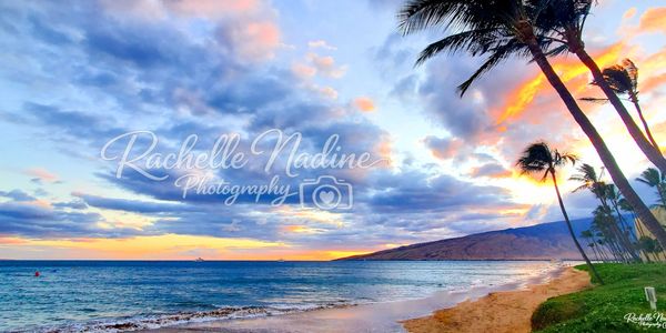 Sunset over a tropical beach with palm trees and colorful skies. Sugar Beach, Kihei, Maui, Hawaii.