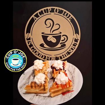 Waffles topped with whipped cream and syrups, served on a white plate.