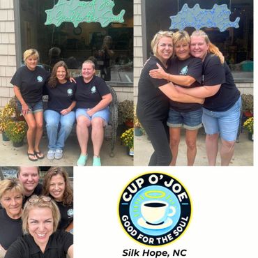 Three women smiling outside a coffee shop with a neon sign and logo.