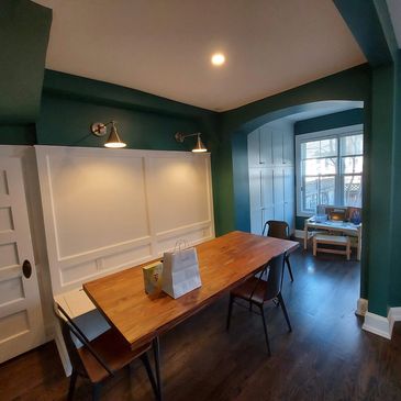 Cozy dining area with green walls and wooden table.