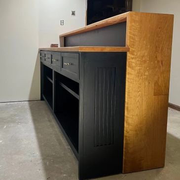 Black and wood kitchen island with drawers and shelves.