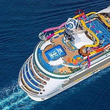 A colorful cruise ship with water slides in the ocean.