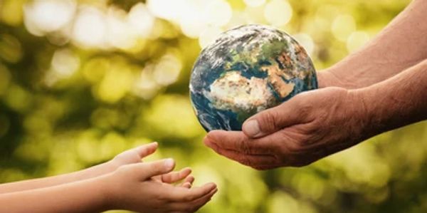 Hands passing a small globe, symbolizing care for the Earth.