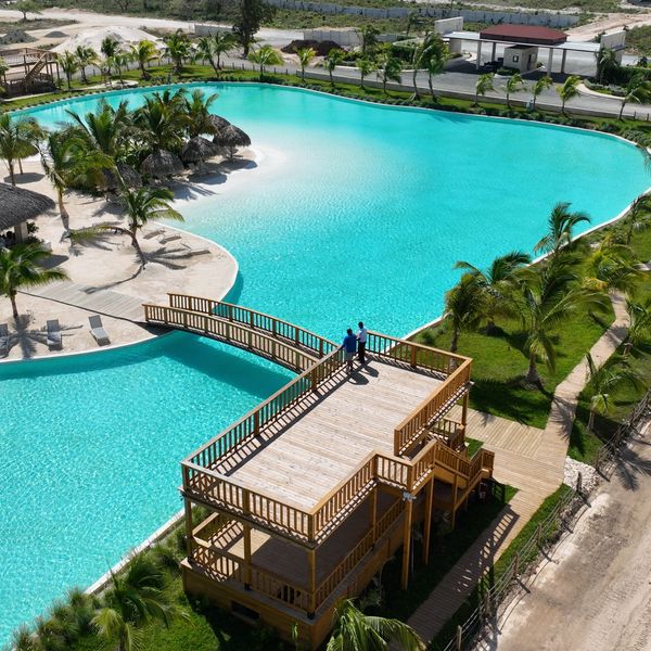 Gran piscina con áreas de descanso y palapas.