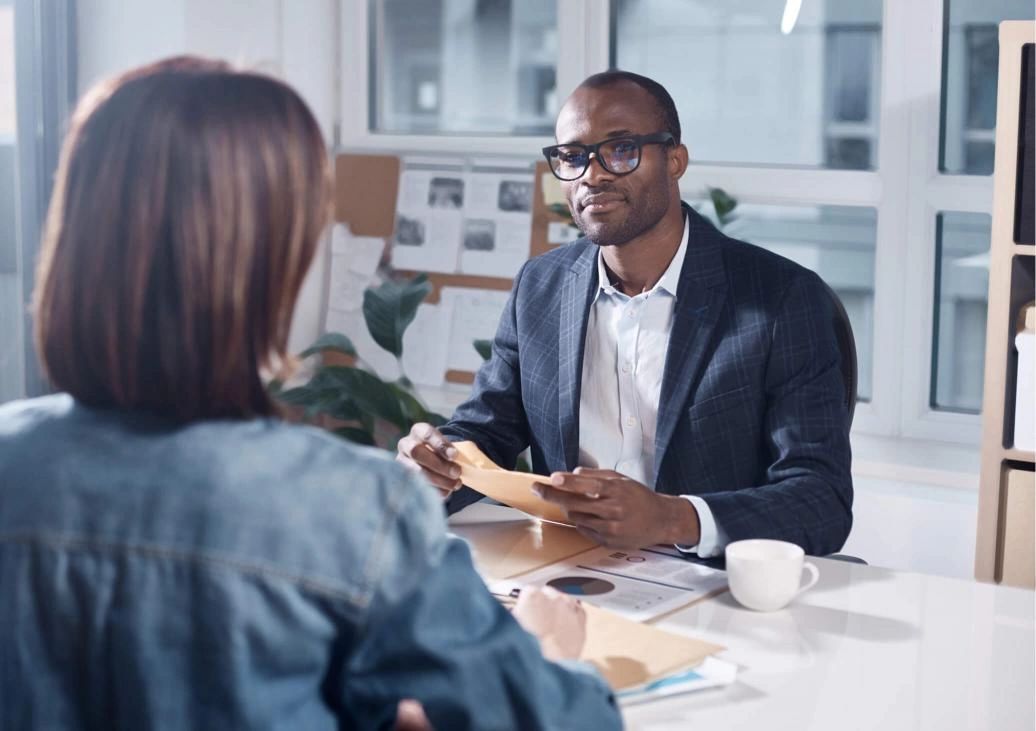 Black man consulting and showing information to a white women. They are having a business meeting