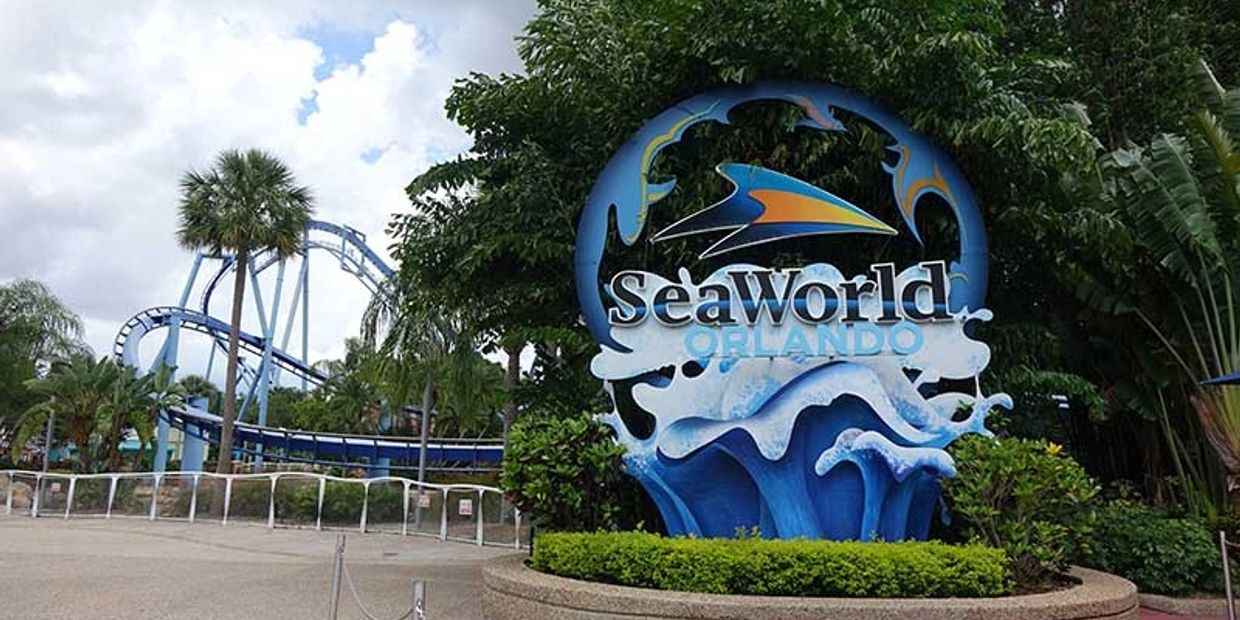 SeaWorld Orlando entrance sign with roller coaster in background.