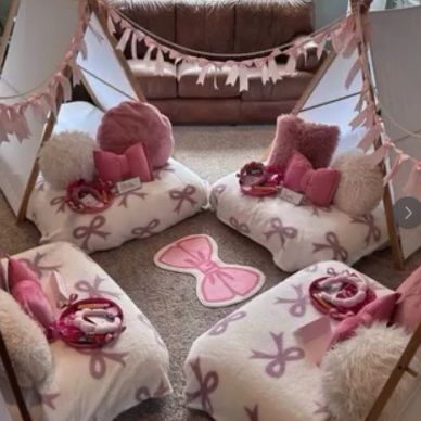 Cozy pink-themed indoor teepee setup with cushions and blankets.