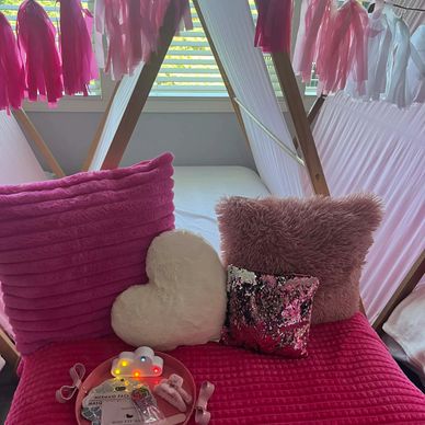 Cozy pink-themed seating area with decorative pillows and fairy lights.