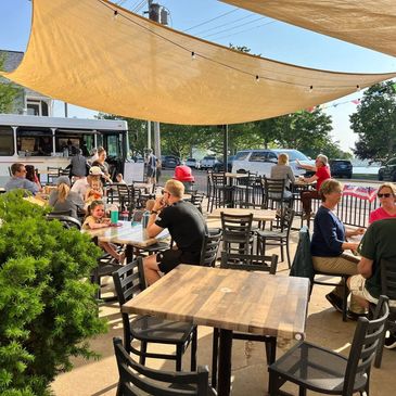 People dining outdoors under shade sails on a sunny day.