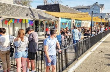 People socializing at outdoor café seating on a sunny day.