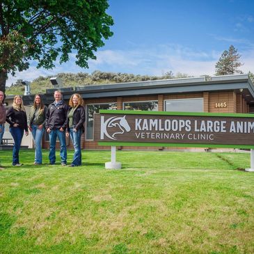 Group of people standing near a veterinary clinic sign outdoors.