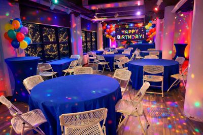 Colorful birthday party setup with balloon decorations and blue-covered tables.