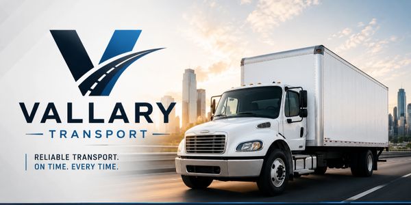 White transport truck driving in city with Vallary Transport logo and slogan.