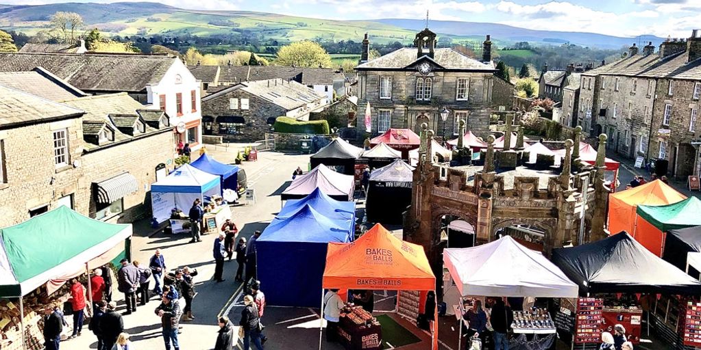 A vibrant outdoor market with colorful tents in a historic town square.