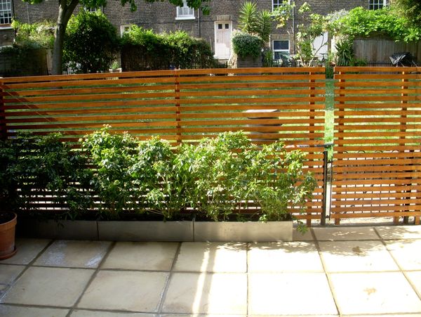 A wooden fence with plants in the front