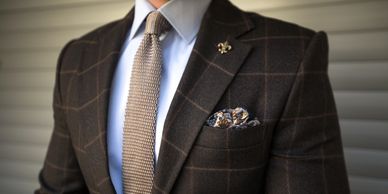 A picture of a brown sport coat, crisp white shirt with a matching silk tie.