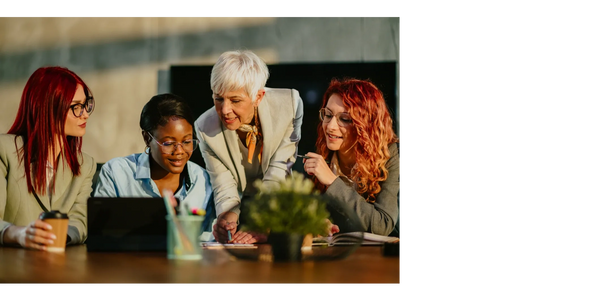Four women looking at a report on the top of the table together.