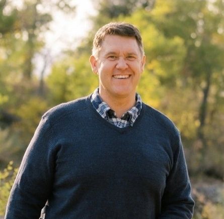 Man smiling outdoors in casual wear.