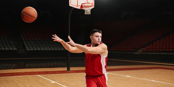 Basketball player in red passing the ball on an indoor court.