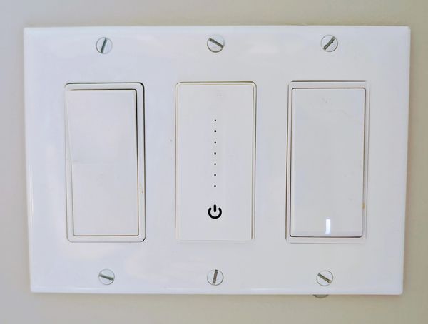A standard switch, a smart dimmer and a smart light switch in a standard three-gang box