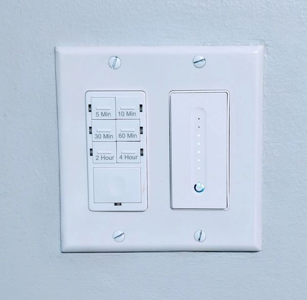 A bathroom fan timer and smart dimmer in a standard two-gang box