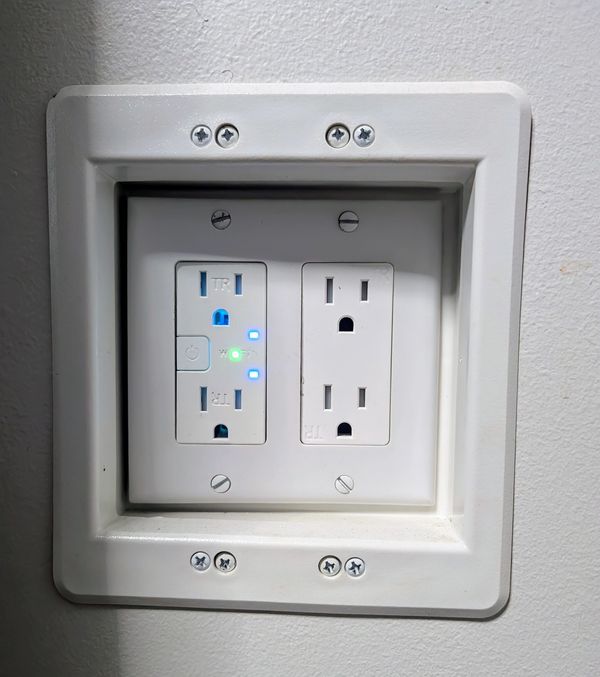 Recessed smart outlet allows power control behind wall-mounted devices like TVs. This outlet is inst