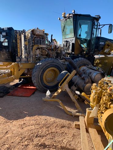 Heavy machinery under repair with exposed engine parts on a construction site.
