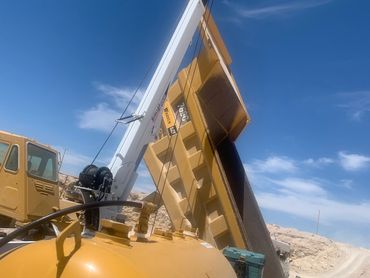 Construction machinery lifting dirt under a clear blue sky.