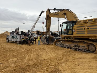 Construction workers operate heavy machinery at a sandy mining site.