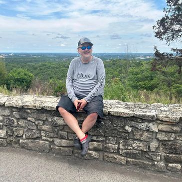 Man sitting on rock wall.