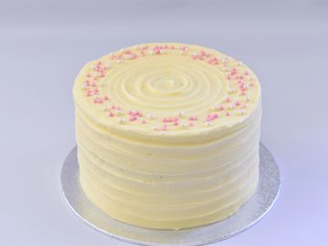 red velvet cake with a cream cheese buttercream covered in pink and white sprinkles