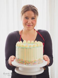 pastry chef in vienna holding custom drip cake with sprinkles and organic dairy 