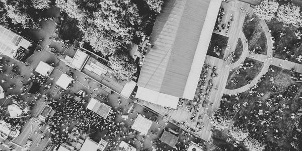 Black and white aerial view of a crowded outdoor event with tents and trees.