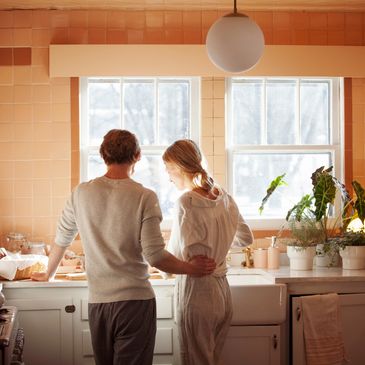 A couple standing together in orange kitchen under warm lighting