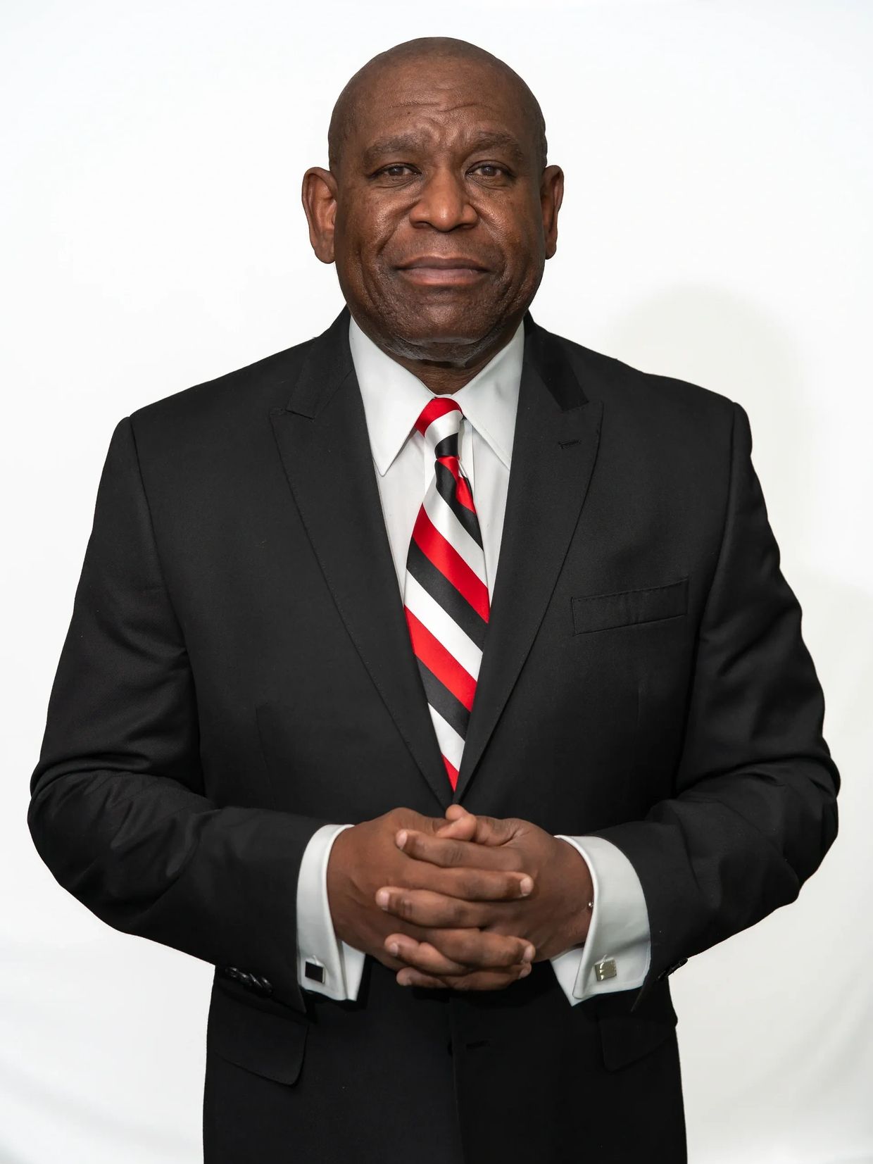 Man in black suit with red, black, and white striped tie.