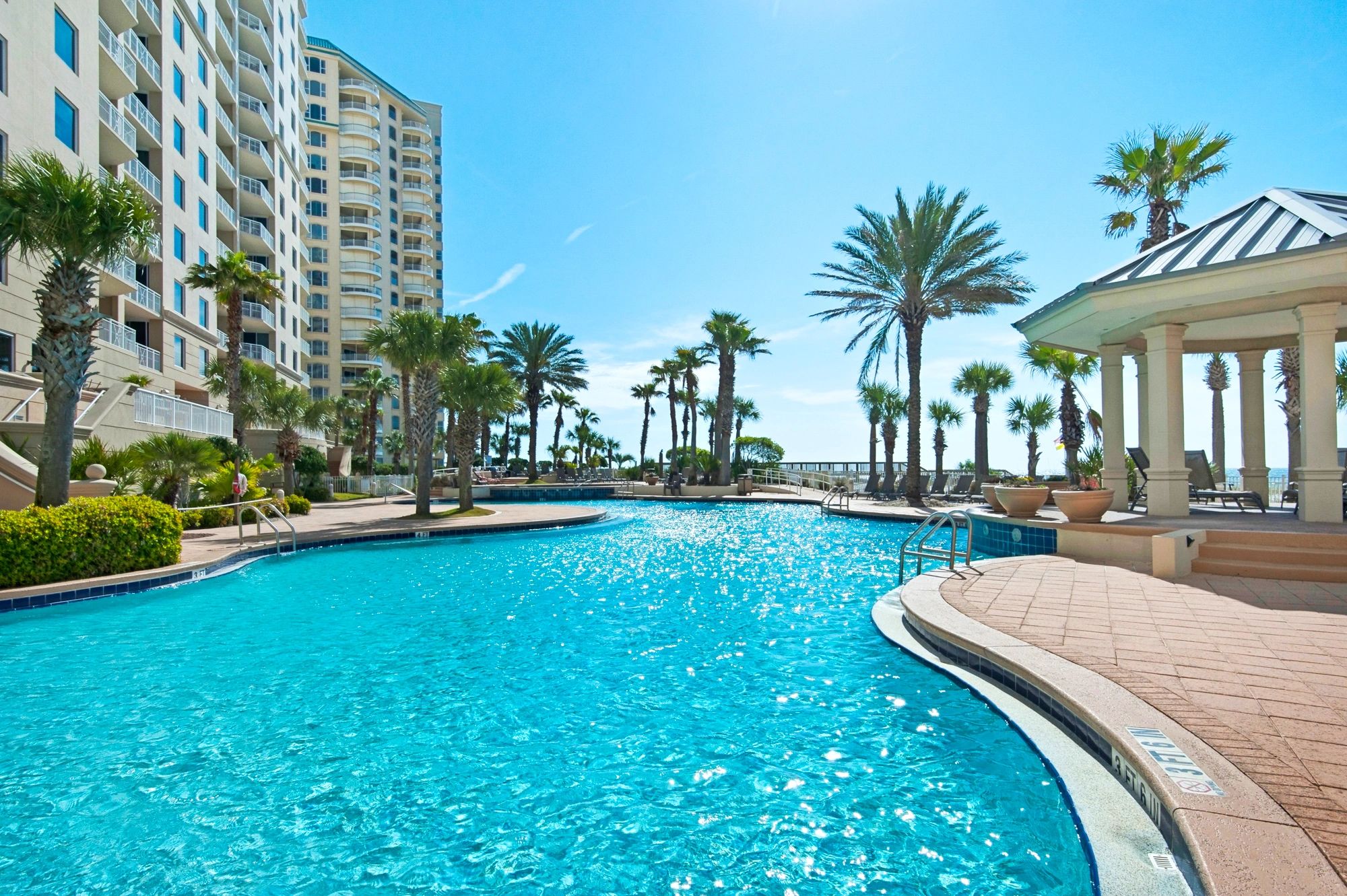 Sunny outdoor pool area with palm trees and lounge chairs, ready to help you find serenity at the beach