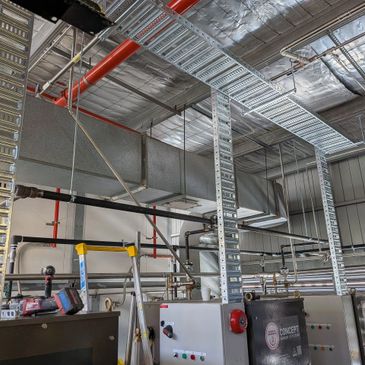 Industrial HVAC ductwork and piping system inside a facility.