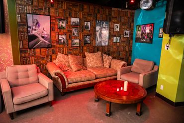 Cozy lounge area with patterned sofa, armchairs, and vintage photo wall.