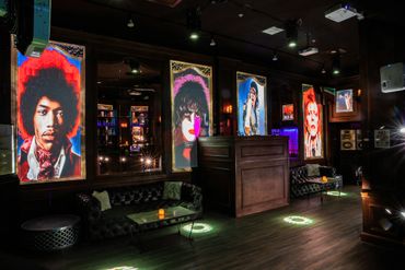 A stylish lounge with illuminated portraits of iconic musicians on the walls.