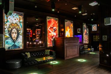 Artistic lounge with illuminated paintings and cozy seating.