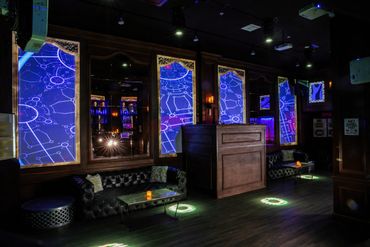 Elegant lounge with futuristic blue light panels and cozy black leather sofas.