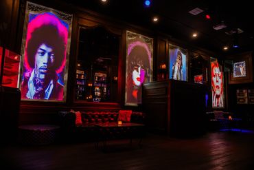 A dimly lit lounge with vibrant portraits of iconic musicians on the walls.