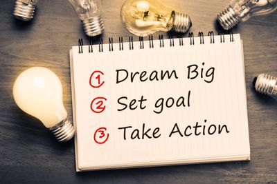 Notebook with steps: Dream Big, Set goal, Take Action.