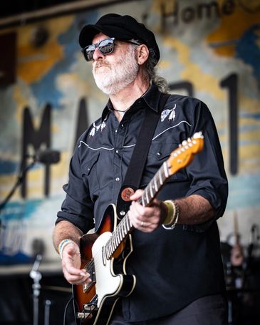 Man playing electric guitar on stage.